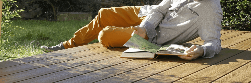 Man met boek op vlonder planken buiten met zon